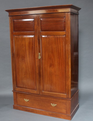An Edwardian mahogany wardrobe with moulded cornice enclosed by panelled doors, the base fitted a drawer and raised on a platform base 202cm h x 134cm w 59cm d 