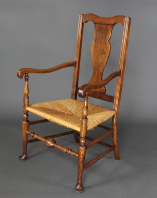 An 18th Century elm slat back open arm carver chair with woven rush seat on pad feet