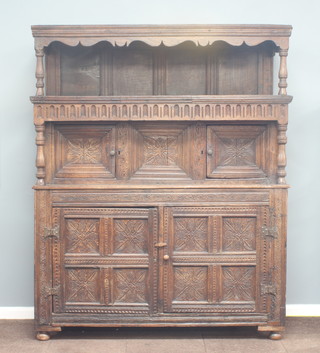 A 17th/18th Century carved oak tridarn, the upper section with recess and cupboard enclosed by panelled doors, the base enclosed by 2 panelled doors, heavily carved throughout and with arcaded decoration 206cm h x 168cm w x 62cm d 