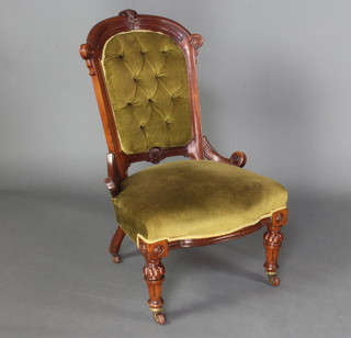 A late Victorian mahogany show frame nursing chair upholstered in green buttoned Dralon raised on turned and reeded supports 