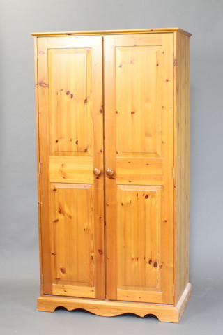 A pine wardrobe enclosed by panelled doors, raised on a platform base 183cm h x 96cm w x 53cm d 