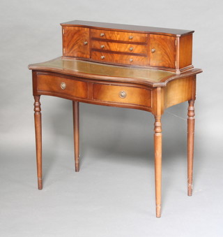 A Georgian style mahogany writing table of serpentine outline with inset writing surface, the raised back fitted 3 long drawers flanked by a pair of cupboards, the base fitted 2 long drawers on turned supports 95cm h x 89cm w x 45cm d  