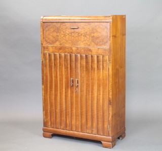 An Art Deco figured walnut cocktail cabinet with hinged lid, the base enclosed by a panelled door 121cm h x 73cm w x 36cm d 