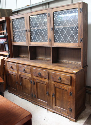 An oak dresser, the raised back fitted 3 cupboards enclosed by lead glazed panelled doors, the base fitted 4 short drawers above a double cupboard, raised on a platform base 183cm h x 183cm w x 44cm d 