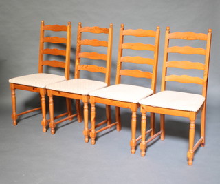 A set of 4 pine ladder back dining chairs with upholstered seats raised on turned and block supports 