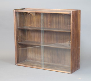 A dark oak bookcase with 3/4 gallery fitted adjustable shelves enclosed by glazed sliding panelled doors 83cm x 91cm x 29cm 