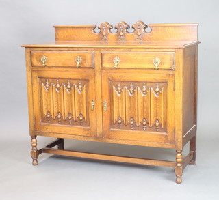 A 1930's carved oak sideboard with raised back, the base fitted two drawers above linenfold doors, raised on turned and block supports 108cm x 122cm x 48cm (some pitting to the top) 