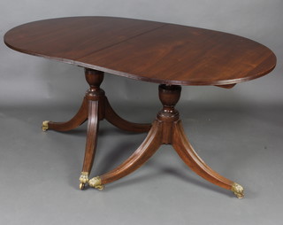 A Georgian style mahogany twin pillar dining table with 2 extra leaves, raised on pillar and tripod supports ending in brass caps and castors 74cm h x 91cm w x 152cm l x 242cm when extended  
