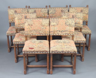 A set of 8 carved oak Cromwellian style dining chairs, the tops carved lion masks with upholstered tapestry seats and backs raised on turned supports with H framed stretcher 