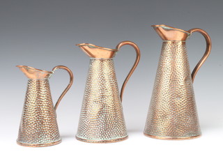 A set of 3 graduated Joseph Sankey and Sons hammered copper jugs of waisted form 27cm, 21cm and 16cm 