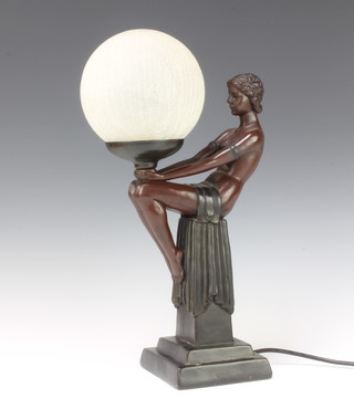 An Art Nouveau style bronzed table lamp in the form of a semi-naked seated girl supporting a frosted glass globe raised on a square base 38cm x 13cm x 13cm 