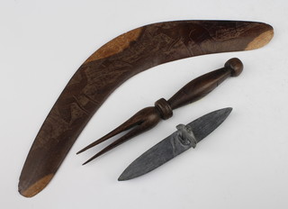 A carved hardwood cannibal fork 21cm, a carved Inuit model of a canoeist 13 cm (f) and a carved boomerang 36cm 
