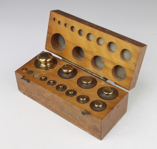 Twelve brass weights - 1kg, 500g, 200g (x2), 100g, 50g, 20g (x2), 10g and 3 others contained in a beech framed box 