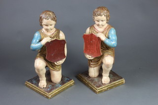 A pair of 18th/19th Century carved and painted wooden figures of kneeling boys holding shields, raised on square bases 60cm x 28cm x 28cm 