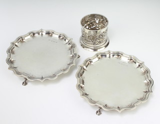 A pair of Edwardian silver card trays with Chippendale rims and hoof feet, Birmingham 1906, 17cm together with a pierced silver bottle holder, 470 grams
