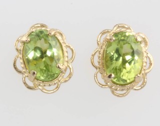 A pair of yellow gold oval peridot ear studs 10mm 