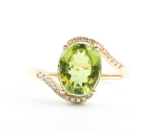 A 14ct yellow gold oval peridot ring approx. 2.4ct with diamond set shank approx 0.3ct, size M 1/2