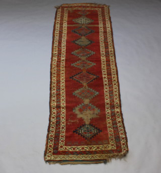 A brown and green ground Caucasian style runner with 10 stylised diamonds to the centre within a 3 row border, heavily in wear, damage to 1 end and fringe missing 310cm x 87cm 