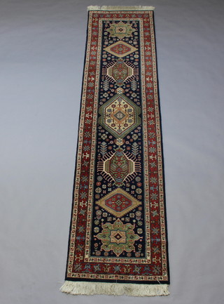 A blue, green and brown ground Heriz runner with 7 medallions to the centre within a 3 row border 310cm x 76cm 