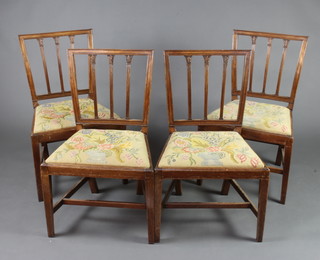 A set of 4 Georgian mahogany stick and rail back dining chairs with Berlin woolwork drop in seats, raised on square tapered supports 