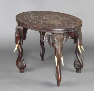 A 19th Century Indian oval carved hardwood occasional table, the central panel decorated elephants and raised on elephant supports 61cm h x 77cm w x 54cm d  