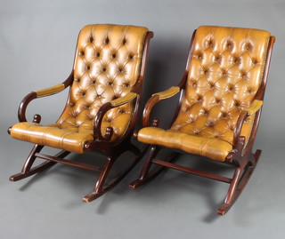 A pair of Regency style mahogany open arm rocking chairs upholstered in light brown buttoned back leather 
