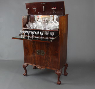 A 1930's walnut Queen Anne style cocktail cabinet the interior fitted with an associated silver plated cocktail shaker, a pair of Webb Brothers cut glass decanters, 5 tumblers, 6 liqueur glasses, 4 sherry glasses, 4 cocktail glasses, a lemon corer and cocktail sticks, the base fitted a cupboard enclosed by a panelled door, raised on cabriole supports 123cm h x 75cm w x 42cm d 