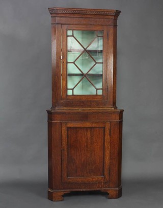 A Georgian oak double corner cabinet, the upper section with moulded and dentil cornice, fitted shelves enclosed by an astragal glazed panelled door, the base enclosed by a panelled door raised on bracket feet 188cm h x 77cm w x 54cm d  
