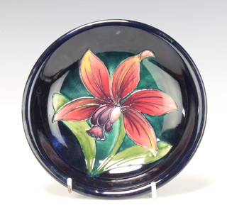 A Moorcroft circular blue ground dish decorated a flower with monogram, signature, impressed and paper label 28cm 