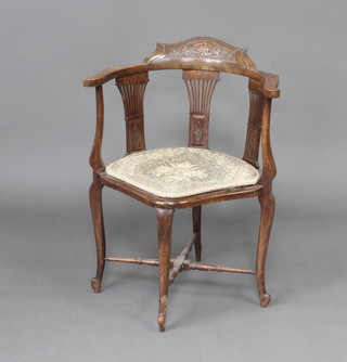 An Edwardian carved walnut corner chair with pierced slat back and upholstered seat raised on cabriole supports with H framed stretcher 