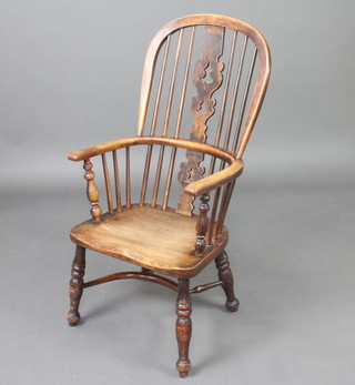 A 19th Century elm stick back Windsor carver chair with solid elm seat and cow horn stretcher, raised on turned supports 