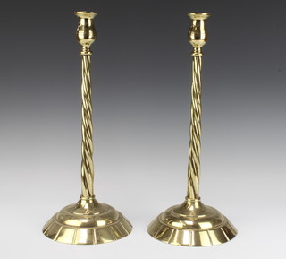 A pair of brass spiral turned candlesticks raised on circular bases 43cm h x 19cm diam.