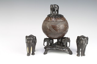 A cup and cover formed from a coconut supported by 3 elephants and with elephant finial 26cm x 14cm together with a pair of ebony figures of standing elephants 10cm, 1 other 3cm  and a carved wooden figure of a seated man 5cm 