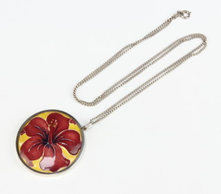 A silver mounted circular Moorcroft hibiscus pendant on a ditto chain 