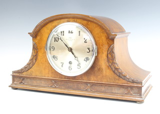 A 1930's chiming mantel clock with silvered dial and Arabic numerals contained in an arch shaped carved walnut case 