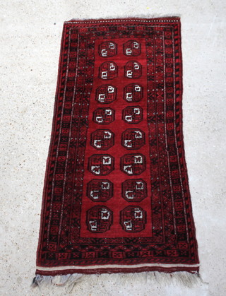 A red and black Afghan rug with 16 octagons to the centre within a multi row border 165cm x 78cm 