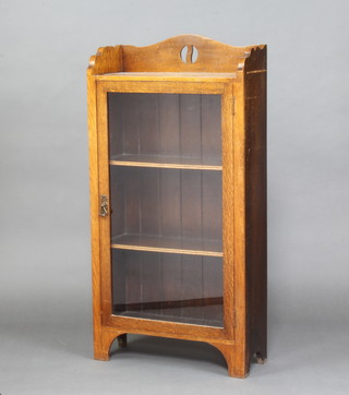 A 1920's Liberty style oak display cabinet with 3/4 gallery, the interior fitted shelves enclosed by a glazed panelled door 104cm x 53cm w x 21cm d  