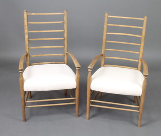A pair of Arts and Crafts  beech ladder back open arm chairs with over stuffed seats, raised on turned supports 