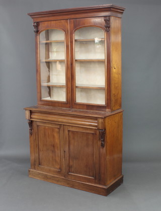 A Victorian mahogany bookcase on cabinet with moulded cornice, fitted adjustable shelves enclosed by arched panelled doors, the base fitted a drawer above panelled doors, raised on a platform base 207cm h x 112cm w x 49cm d 