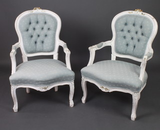 A pair of white and blue painted French open arm salon chairs with upholstered seats and backs, raised on cabriole supports 