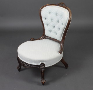 A Victorian carved mahogany show frame nursing chair, upholstered in blue buttoned material, raised on cabriole supports 