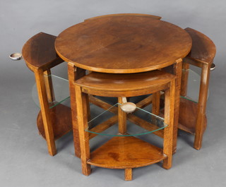 An Art Deco circular walnut table incorporating 4 interfitting coffee tables with middle glass shelves and attached ashtrays 
