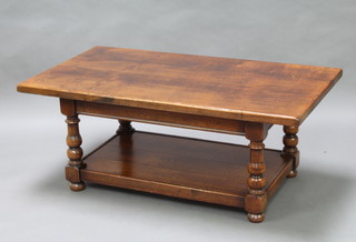 A rectangular solid oak 2 tier coffee table raised on turned supports, bun feet 50cm h x 123cm w x 68cm 