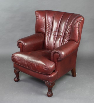 A Georgian style winged armchair upholstered in red leather and raised on carved  cabriole supports