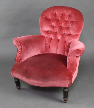 A Victorian armchair upholstered in pink buttoned material, raised on turned supports 
