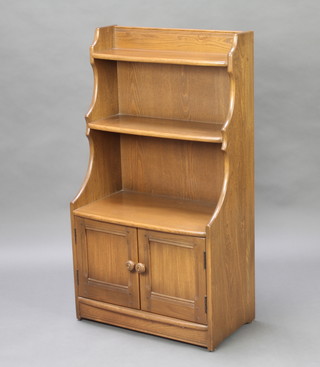An Ercol dark elm waterfall bookcase, the base fitted 2 cupboards 112cm h x 60cm w x 34cm d 
