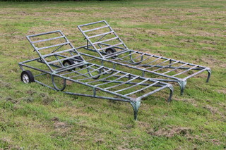 A pair of verdigris metal garden sun loungers raised on cabriole supports and wheels 29cm x 84cm w x 59cm d 