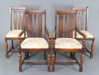 A set of 4 1930's oak stick and rail back dining chairs comprising 2 carvers and 2 standard with upholstered drop in seats, raised on cup and cover supports 