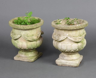 A pair of circular concrete garden urns with swag decoration raised on square feet 34cm h x 29cm 