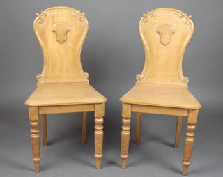 A pair of Victorian light oak hall chairs with solid backs and seats 